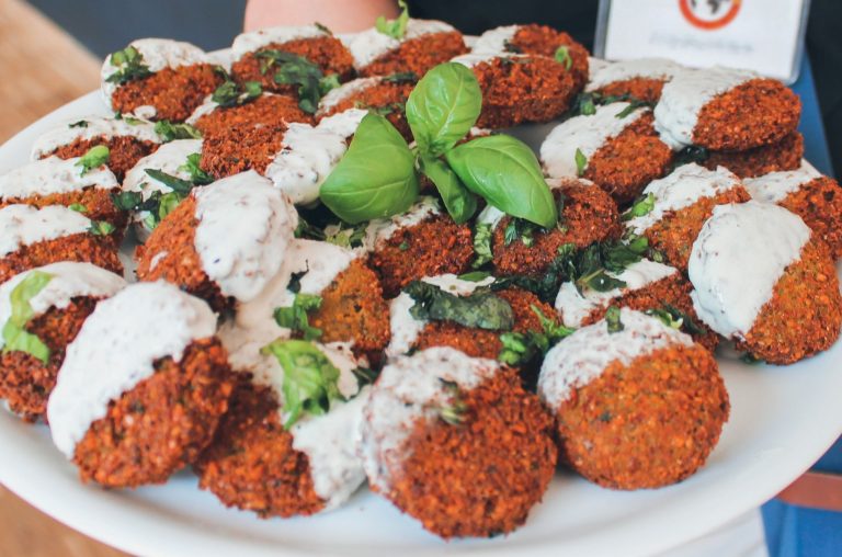 Ein Falafelteller mit weißer Sauce und frischen Basilikumblättern garniert, perfekt für eine kulinarische Stadtführung durch Berlins pulsierenden Stadtteil Kreuzberg.