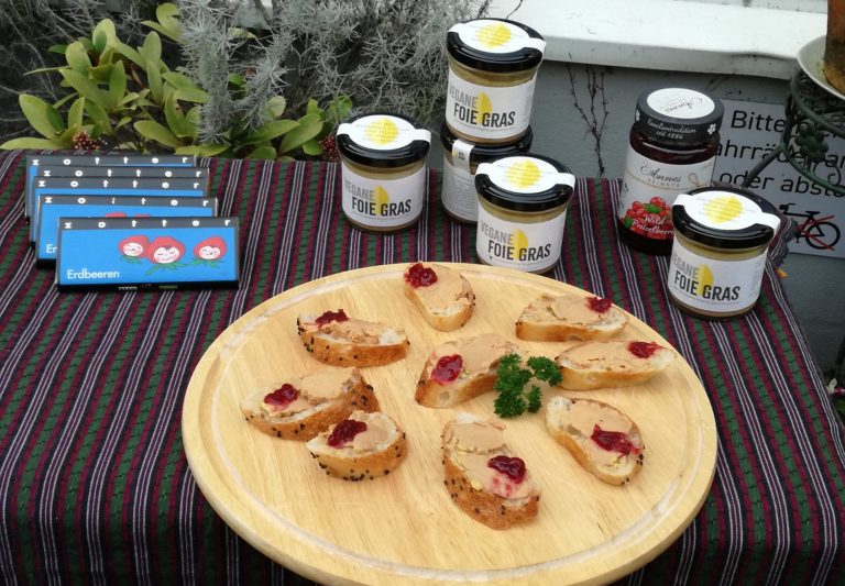Auf einem gestreiften Tischtuch sind Brotscheiben mit Foie gras und Gelee sowie Gläser mit Foie gras und Schokolade kunstvoll angerichtet – ein köstlicher Genuss, der an die Entdeckungen während einer kulinarischen Stadtführung durch Freiburgs charmantes Wiehre-Viertel erinnert.