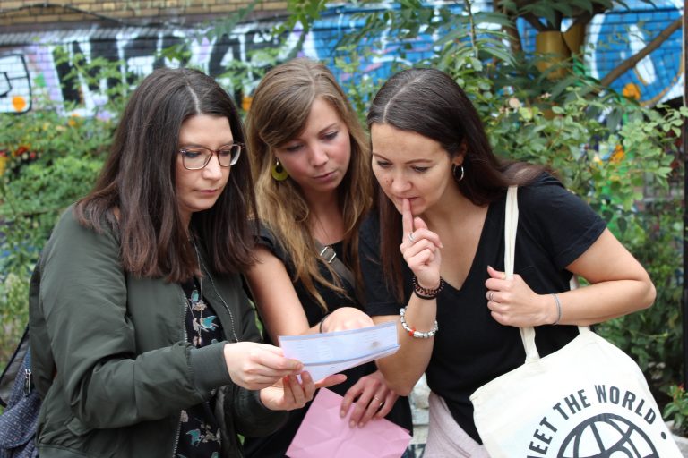 Drei Frauen, die sich während einer Stadtrallye in Münster ein Dokument genau ansehen.