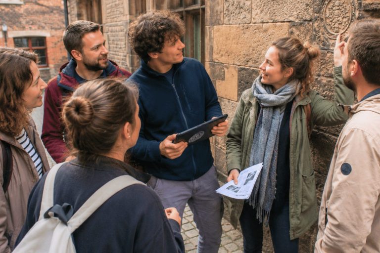 Sechs junge Erwachsene stehen draußen in der Bremer Altstadt, untersuchen eine Steinmauer und schauen sich im Rahmen eines Outdoor-Escape-Games gemeinsam Zettel und ein Tablet an.