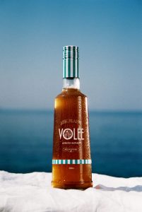 Eine Flasche Volee-Getränk auf einer weißen Oberfläche mit blauem Meer- und Himmelshintergrund.