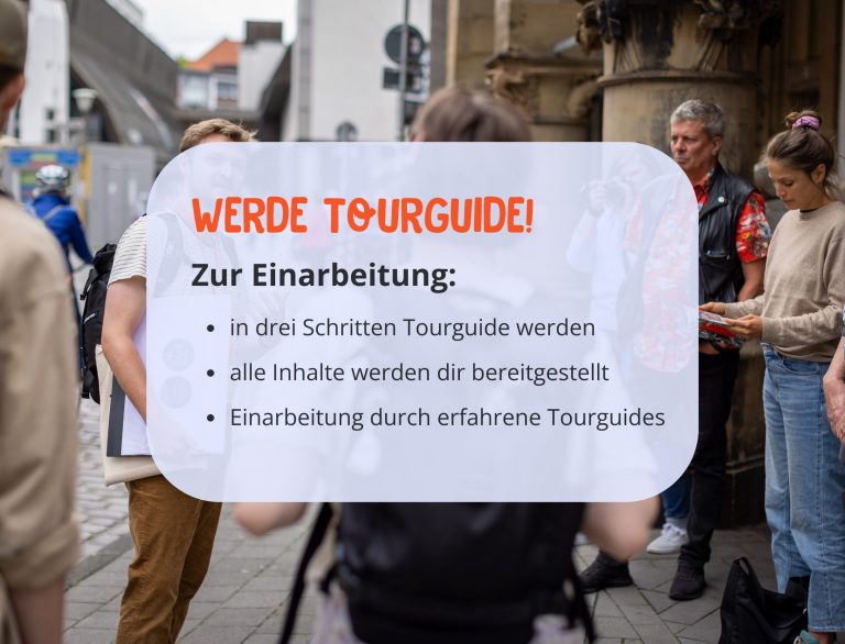 Eine Gruppe von Menschen steht draußen, während ein Schild Informationen über die Ausbildung zum Fremdenführer in deutscher Sprache anbietet.