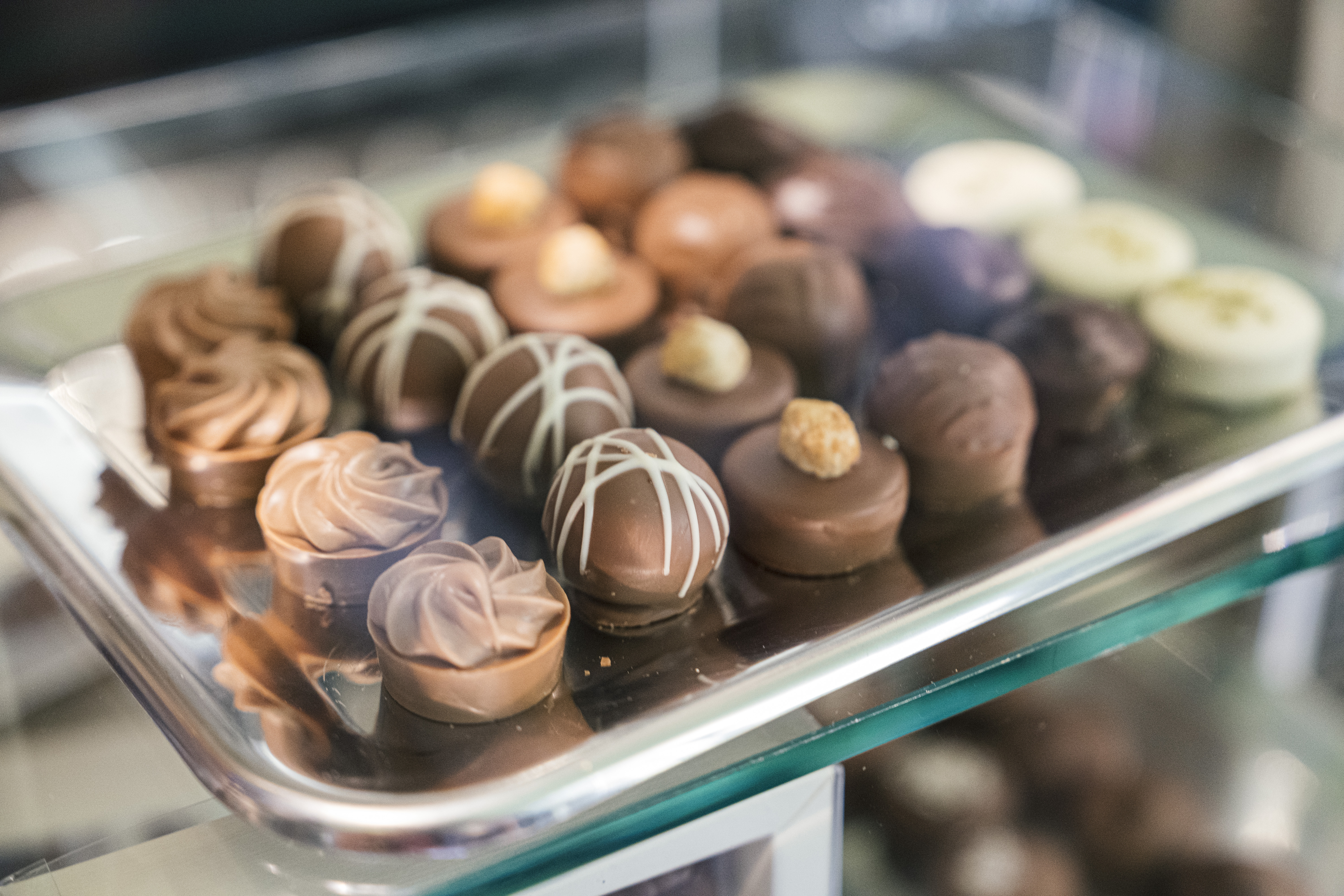 Ein Tablett mit verschiedenen Gourmet-Schokoladen, darunter Vollmilch-, Zartbitter- und weiße Sorten, in einer Glasvitrine - perfekt für schöne Date-Ideen oder süße Date-Ideen Leipzig.