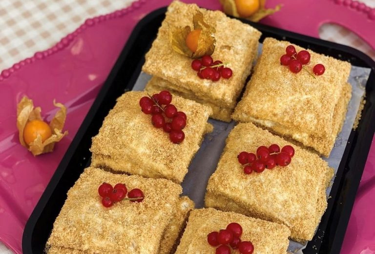 Sechs geschichtete Kuchenscheiben mit roten Johannisbeeren, serviert auf einem Tablett mit rosafarbenem Zierrand - perfekt für eine kulinarische Stadtführung durch den Berliner Wrangelkiez.