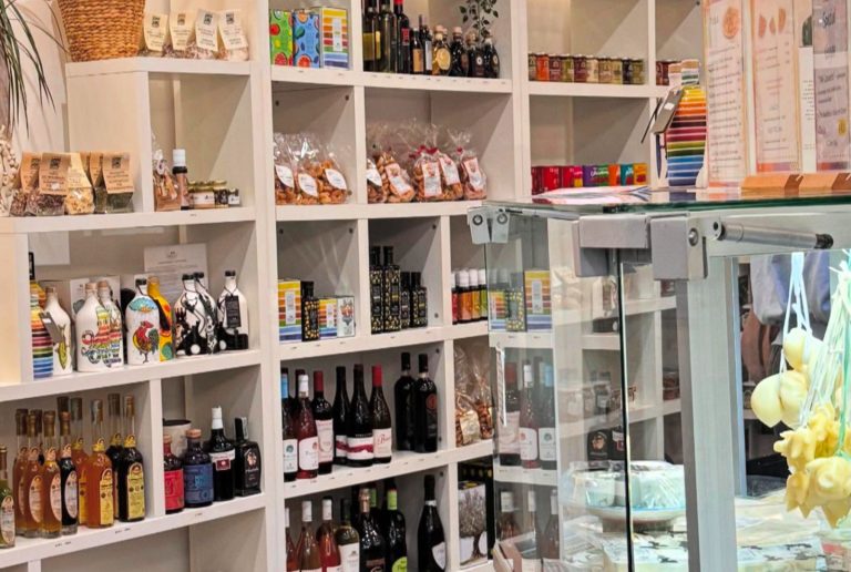 In einem Fachgeschäft warten Regale mit Wein, Soßen und Snacks auf Entdecker und Genießer; vorne steht eine Glasvitrine, in der man den Tag in Heidelberg genießen kann.