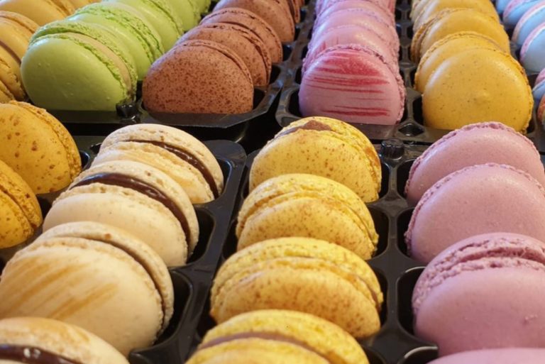 Reihenweise bunte Macarons in schwarzen Tabletts, perfekt für einen Entdecker-Genießer-Tag in Heidelberg - in Gelb, Grün, Rosa, Braun und Creme.