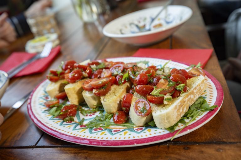 Bruschetta mit Kirschtomaten und Basilikum auf einem gemusterten Teller, serviert auf einem Holztisch - perfekt zum Genießen bei einer kulinarischen Stadtführung durch die Nürnberger Altstadt bei St. Sebald.